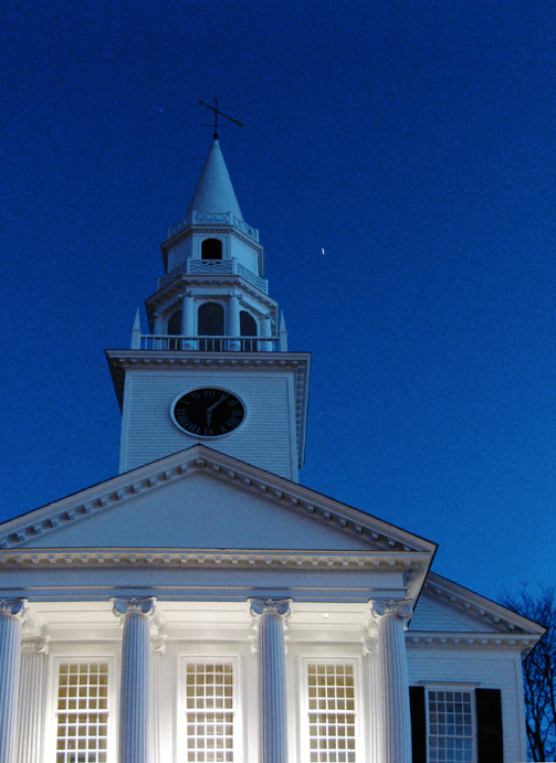 A satellite flares next to a church steeple.