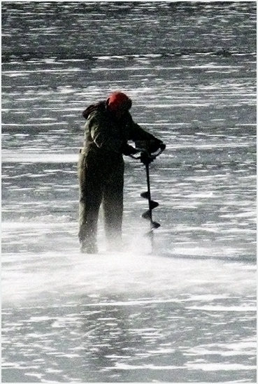 Ice fisherman drilling.